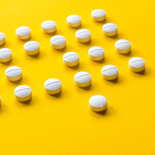 White pills against a yellow backdrop with one missing from the group. -- health coverage from STAT