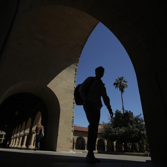A silhouetted person walking on Stanford's campus.