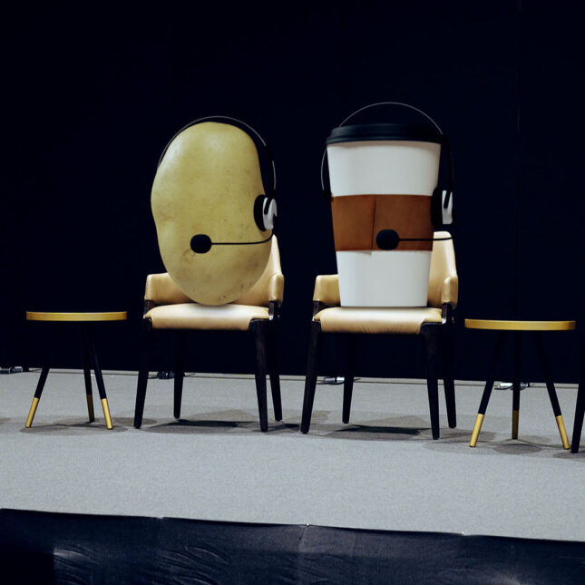 A photo illustration of anthropomorphic foods and drinks sitting on a panel on stage with microphones — policy coverage from STAT