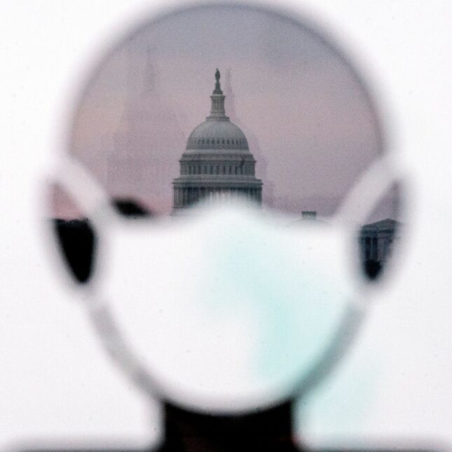 The US Capitol is reflected in a sign calling for protective masks to be worn.