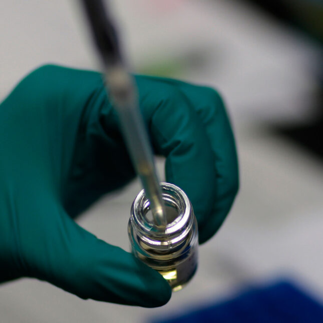 A researcher extracts fluid from a vial. -- health coverage from STAT
